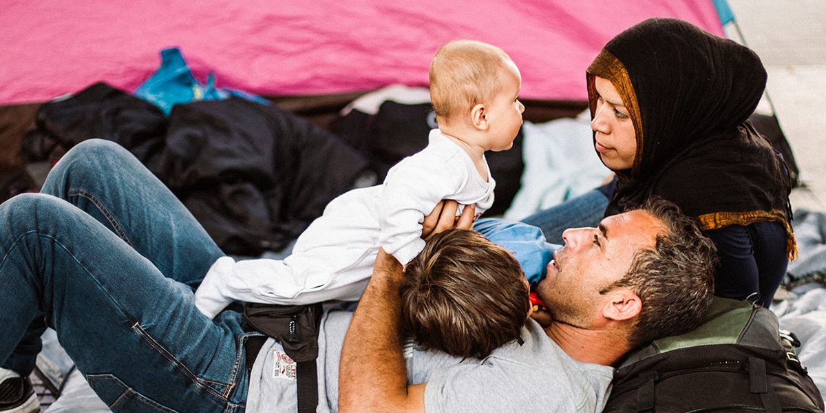 A family lays cuddled close in front of their tent.